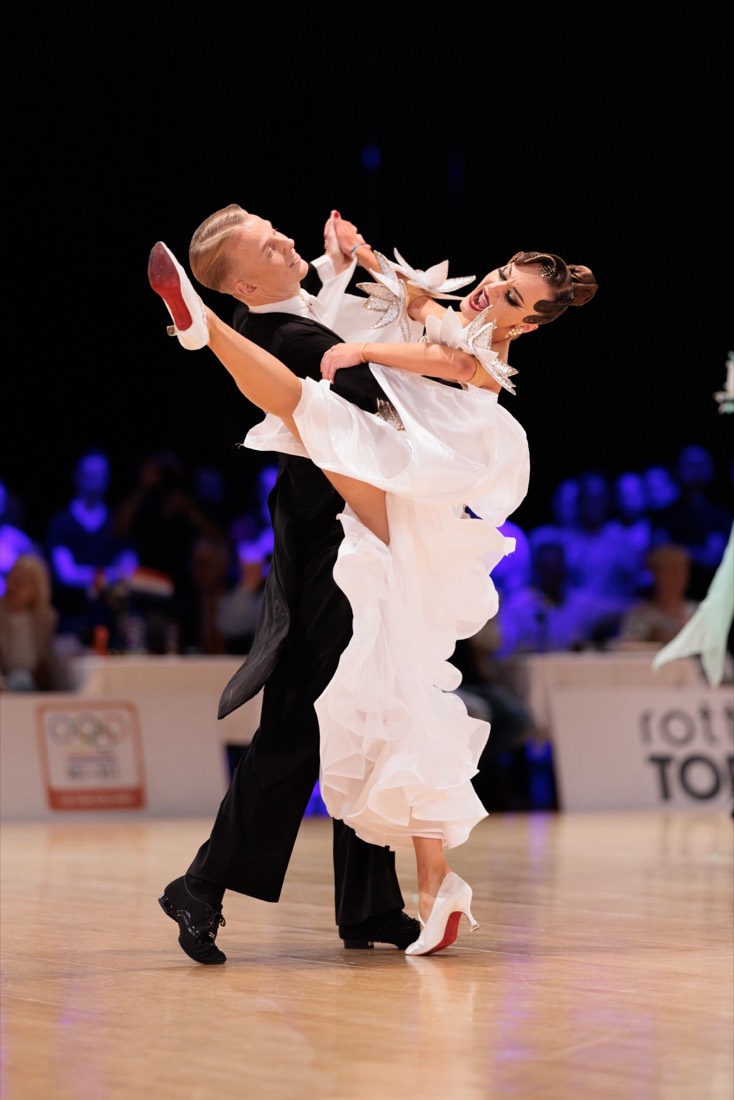 Danseres in witte ballroomjurk met rode dansschoenen