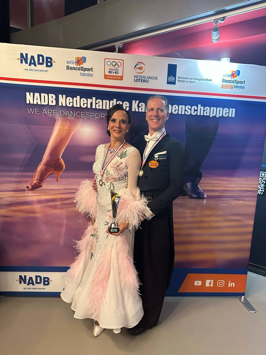 Dansend paar met beker en medailles op de NADB Nederlandse Kampioenschappen